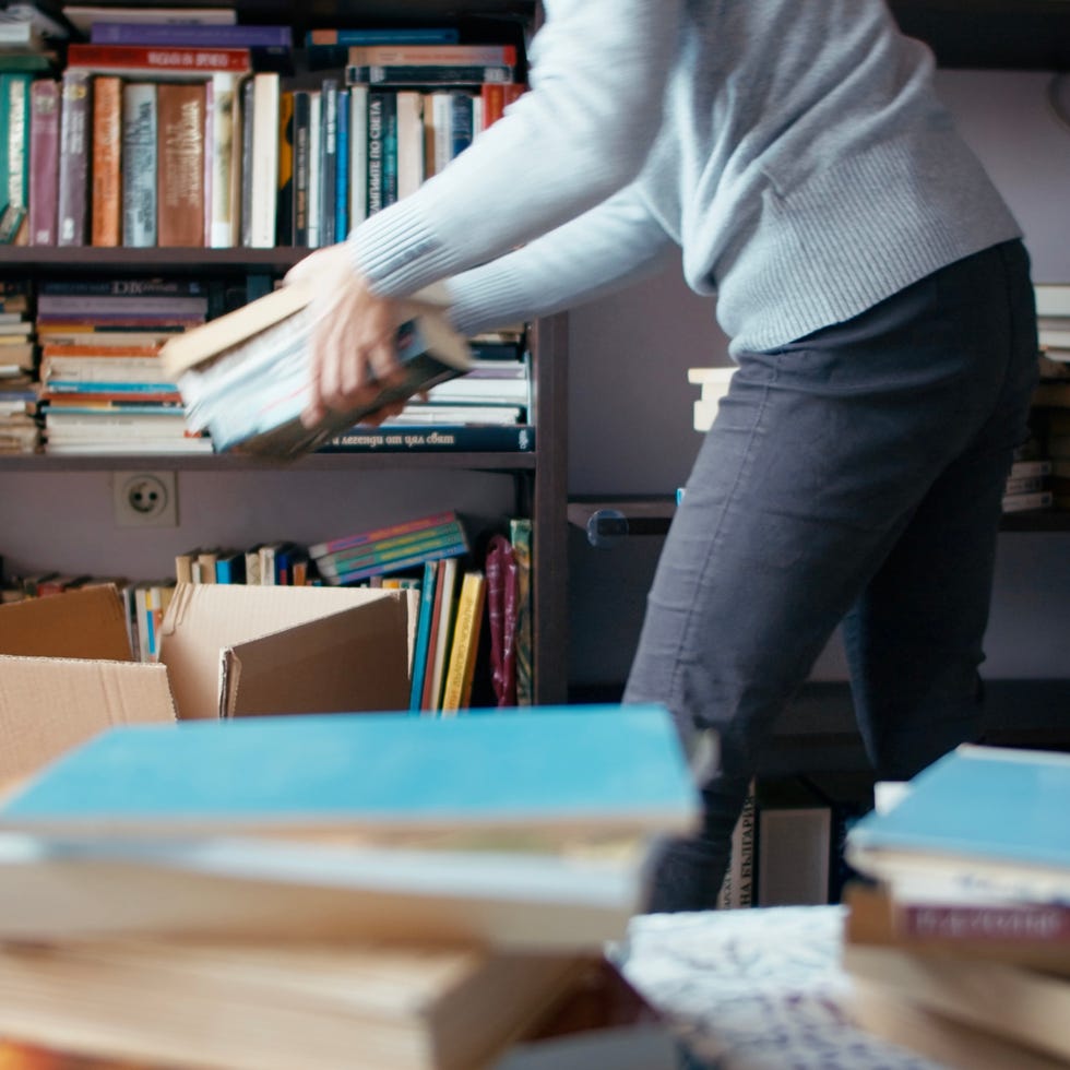 swedish death cleaning, woman packing boxes with books