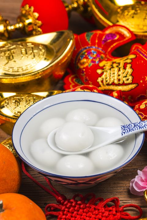 sweet dumplings in bowl on table, ang pow or red packet and gold ingots chinese characters means luck,wealth