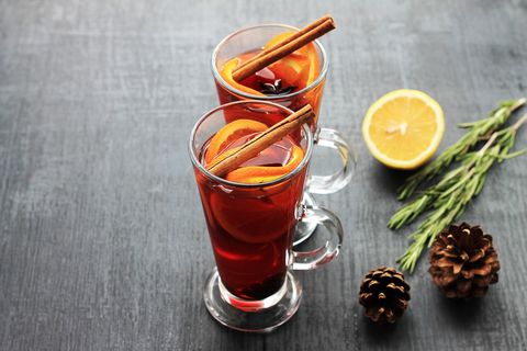 sweet mulled wine for two person in glasses on a black background, decorated fir cones and rosemary