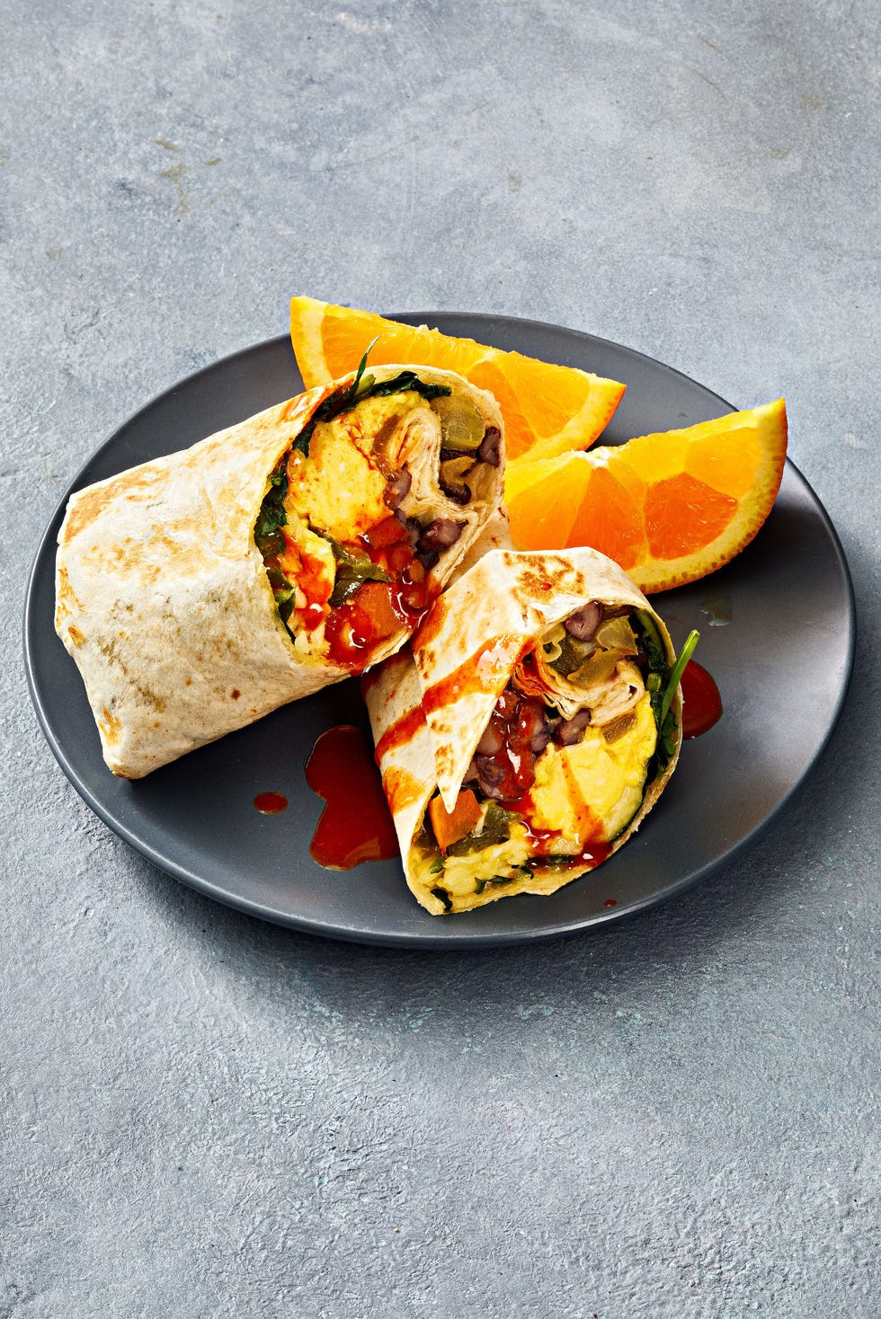 sweet potato breakfast burritos with hot sauce drizzled on top