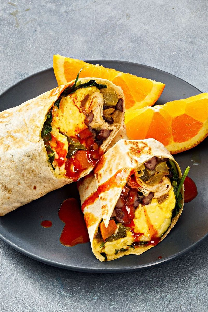 sweet potato breakfast burritos with hot sauce drizzled on top