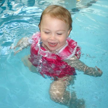 swim diapers toddler swimming in a pool wearing a life vest and swim diaper
