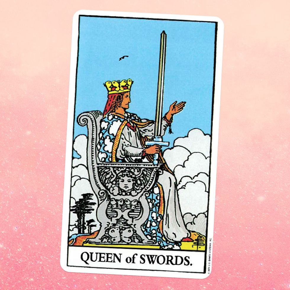 the tarot card for the queen of swords, showing the profile view of a white woman in a white robe, blue and white patterned cape, and gold crown sitting on a silver throne and holding a sword