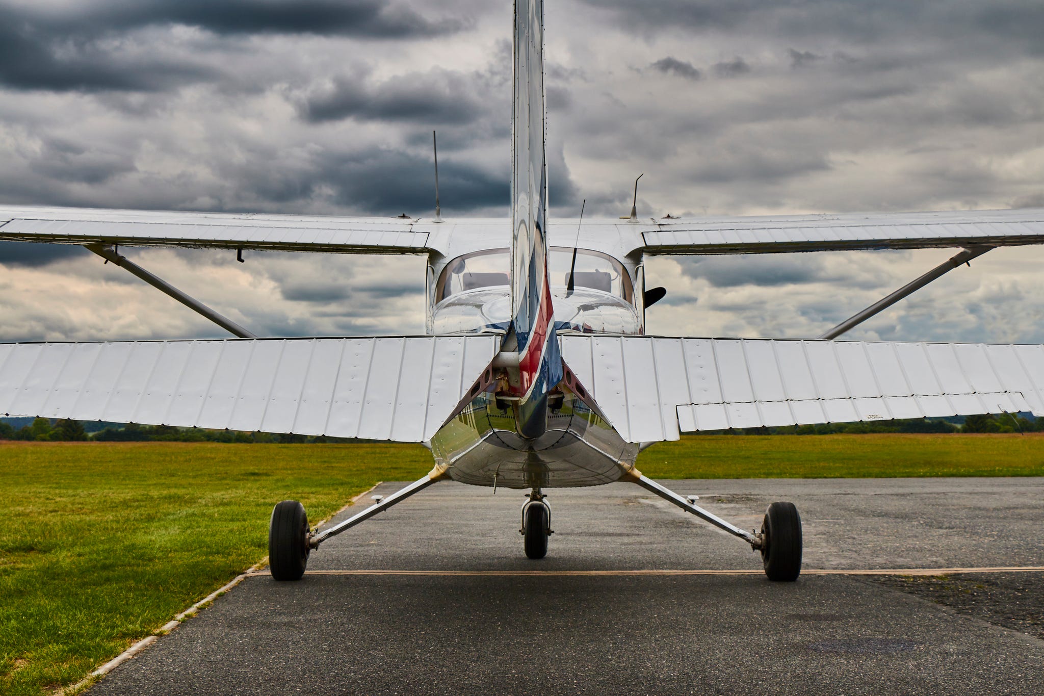 Symmetrical rear view of Cessna 172 Skyhawk 2 airplane on a runway with dramatic sky background.