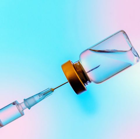 syringe and coronavirus vaccine on blue and pink background