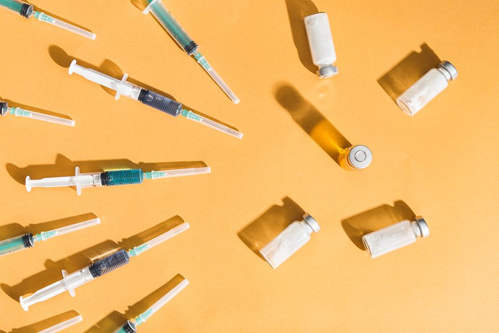 syringes are filled with injection and medical vaccine bottles on a yellow background flat lay