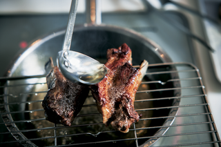 a piece of meat being cooked in a pan