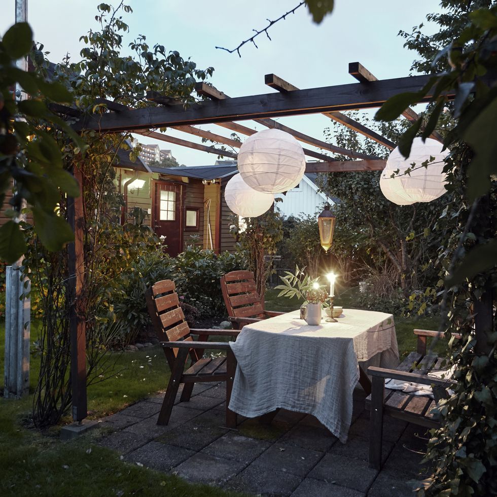 table set in garden under a pergola with paper lanterns