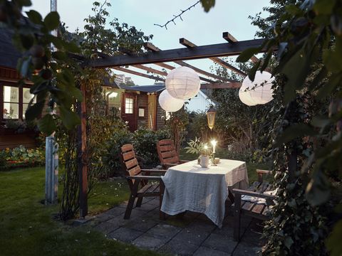 table set in garden under a pergola with paper lanterns