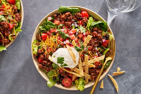 taco salad with sour cream, tomatoes, ground beef, and tortilla strips