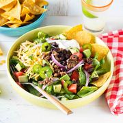 easy taco salad recipe with tortilla chips in yellow bowl on white wood surface with red checkered napkin