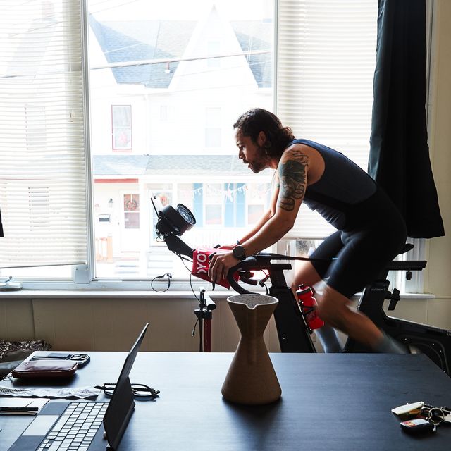 a man rides an stationary bike in front of a large window