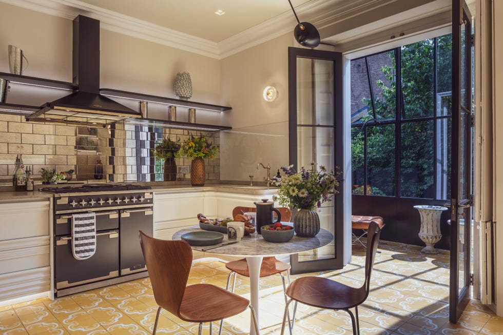 a modern kitchen/diner with mirrored metro tiles leading to a contemporary conservatory with Crittall style glazing