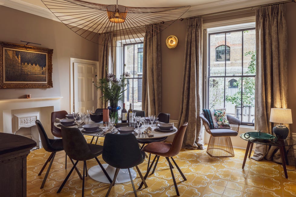 luxurious dining room with patterned tiled floor, a round metallic architectural pendant light and a large oval dining table set for dinner