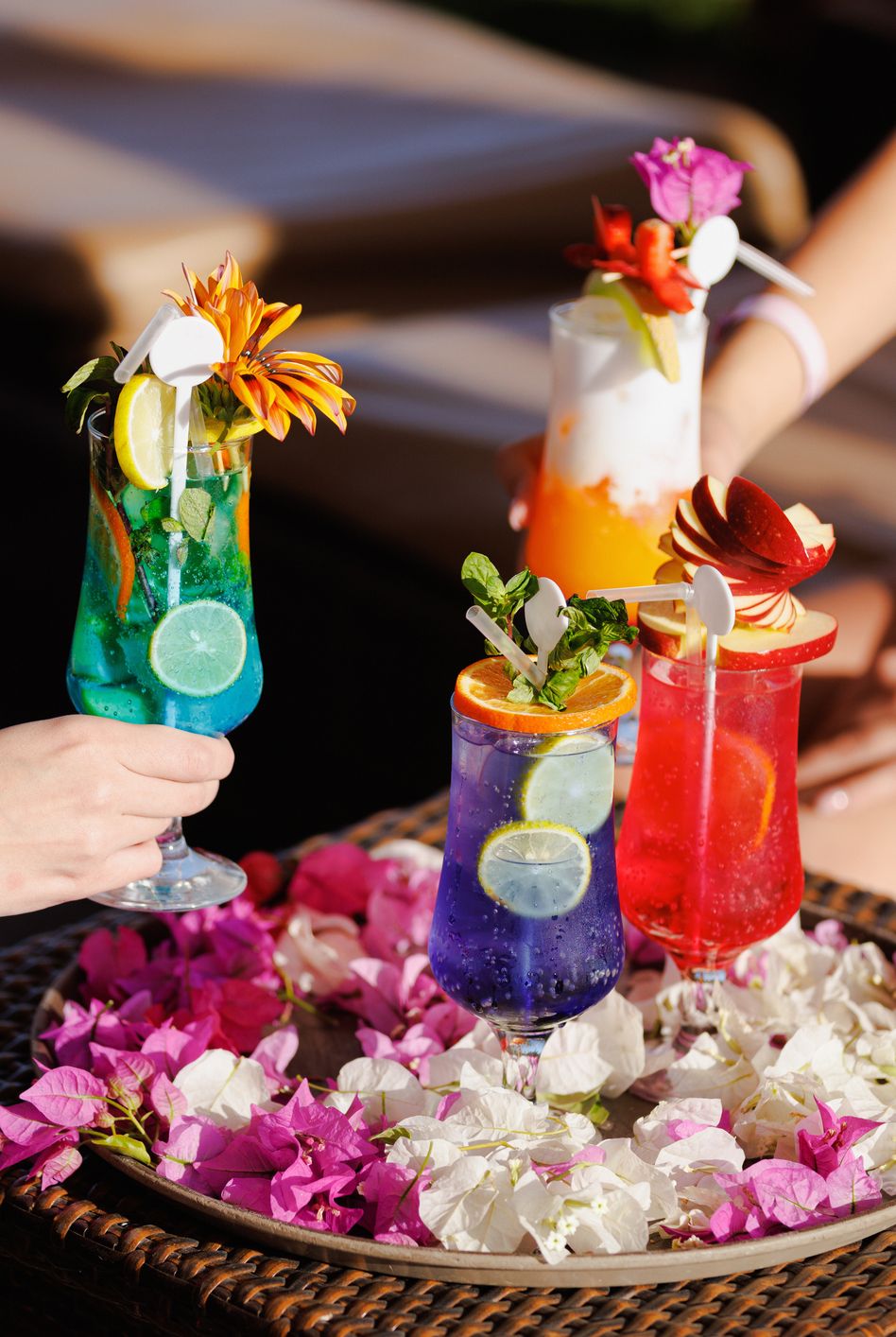 taking various cocktails from tray decorated with petals on bar table