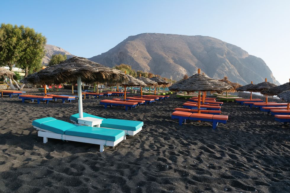 Tanning beds and umbrellas on Perissa beach, Santorini, Greece