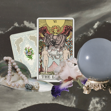 tarot cards surrounded by flowers, a crystal ball, and pearls