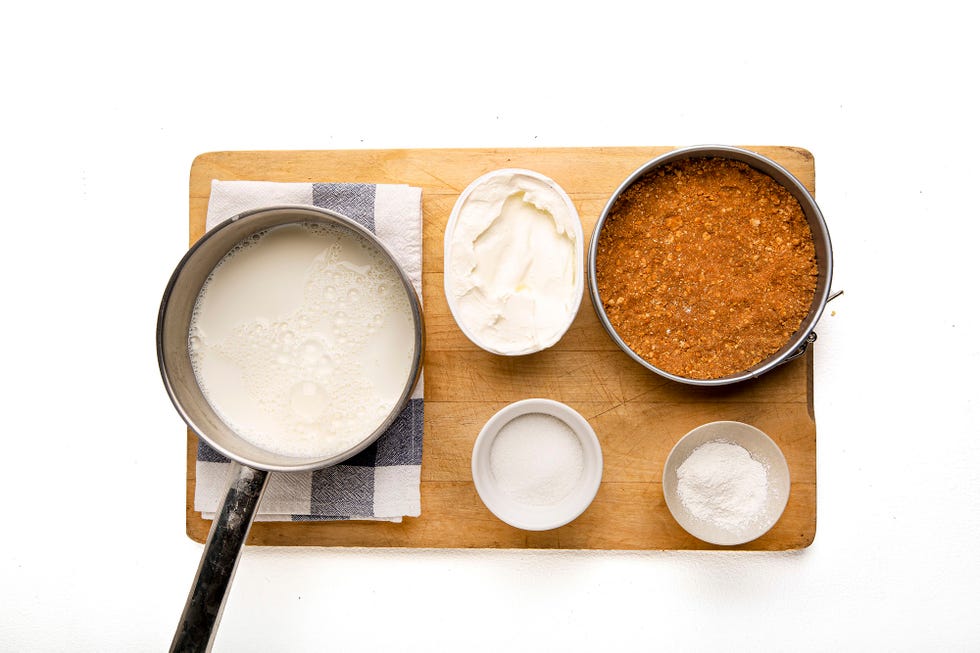 molde con galletas desmijadas y cuencos con queso batido y cazuela con leche
