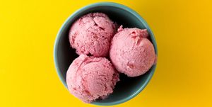 Tasty ice cream vanilla strawberry scoops in blue bowls on yellow vibrant background.