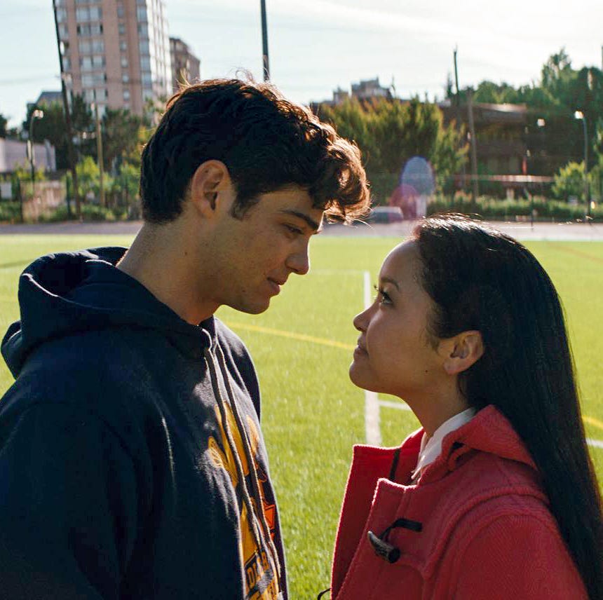 two individuals are positioned closely facing each other on a green soccer field surrounded by buildings and trees two individuals are positioned closely facing each other on a green soccer field surrounded by buildings and trees