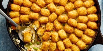 chicken pot pie filling in a skillet topped with tater tots