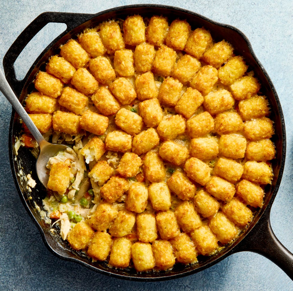 chicken pot pie filling in a skillet topped with tater tots
