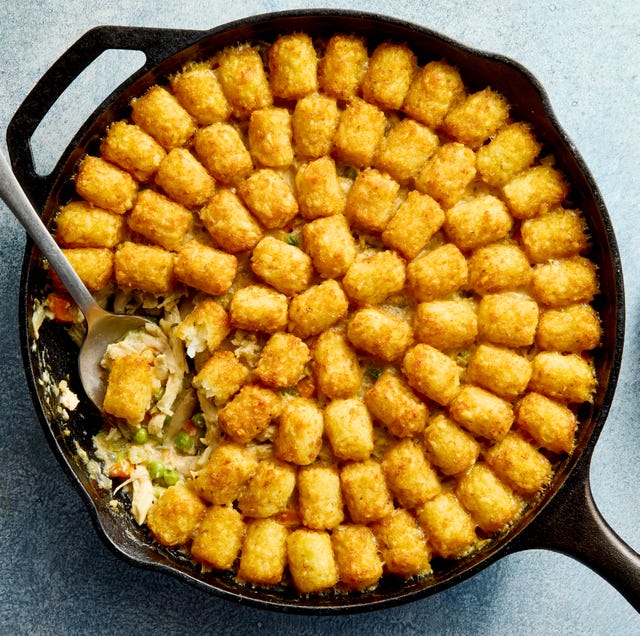 chicken pot pie filling in a skillet topped with tater tots