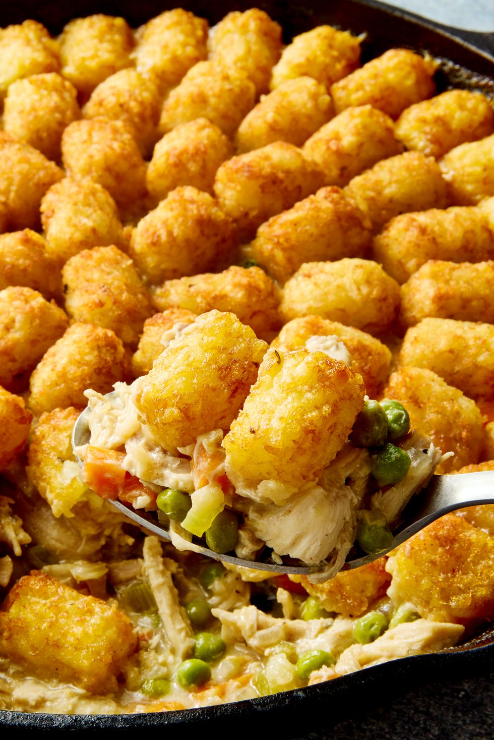 Tater Tot Chicken Pot Pie chicken pot pie filling in a skillet topped with tater tots