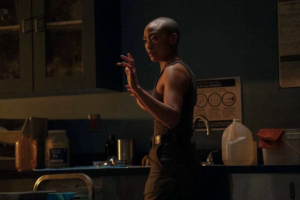 tati gabrielle como nora em pé em uma sala mal iluminada na segunda temporada de the last of us
