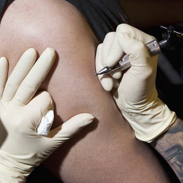 a tattoo artist preparing to tattoo a man's bare arm, close up