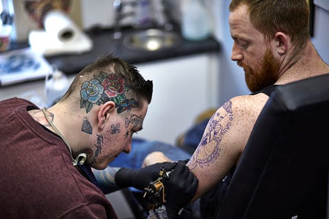 tattoo artist tattooing red headed male