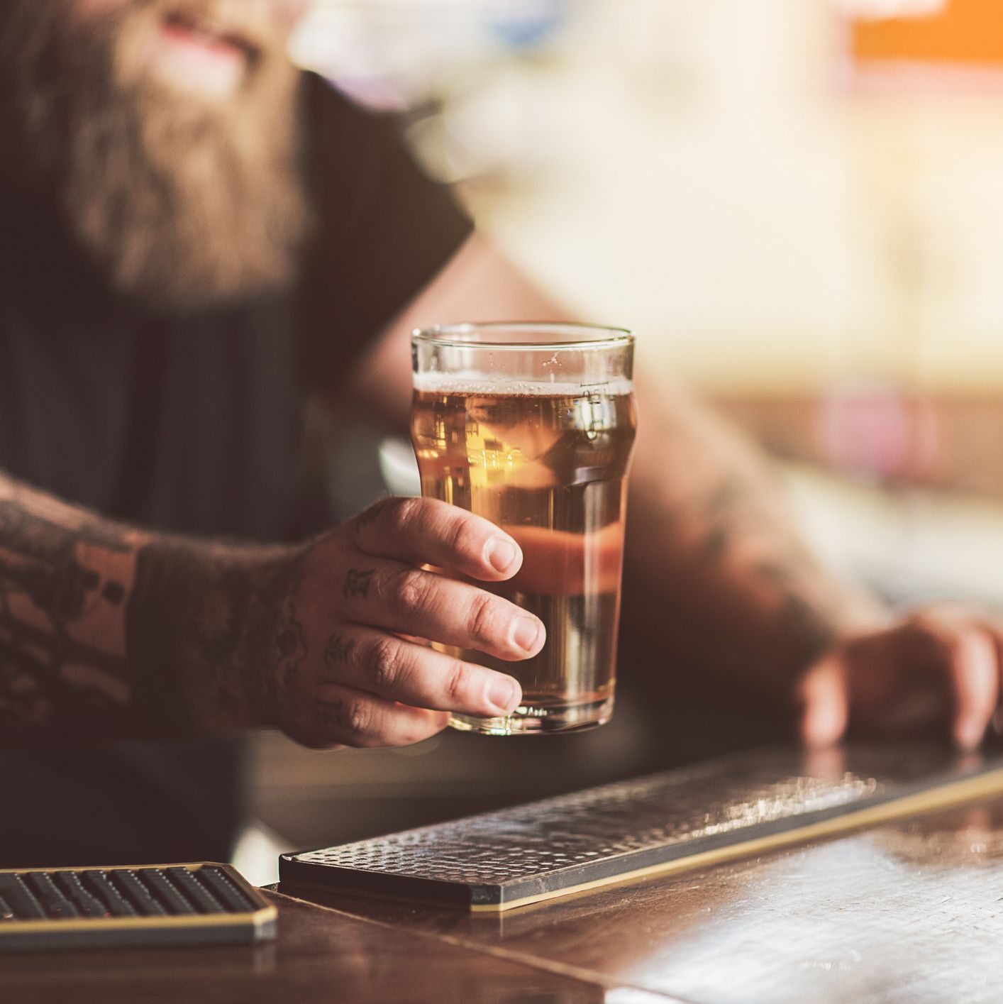 Tattooed bartender with beard working in pub