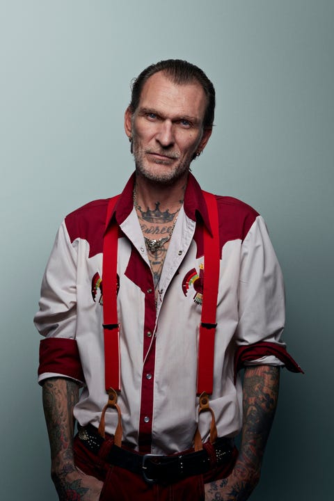 tattooed man in red and white outfit, looking in camera