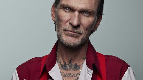 tattooed man in red and white outfit, looking in camera