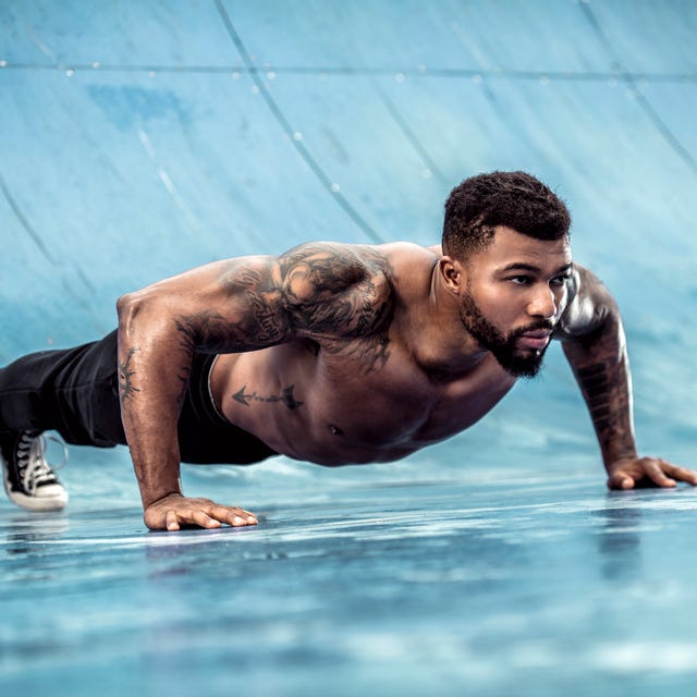 tattooed physical athlete doing pushups on sports field