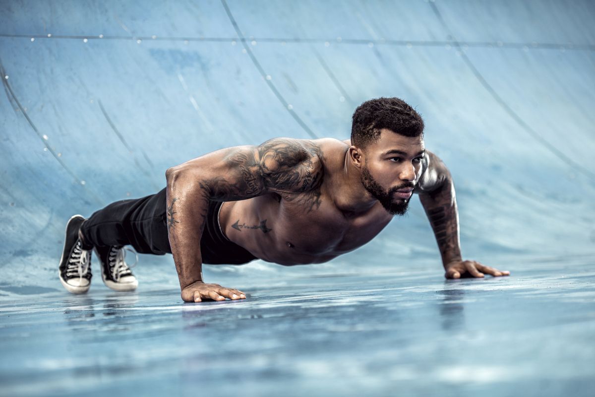 tattooed physical athlete doing pushups on sports field