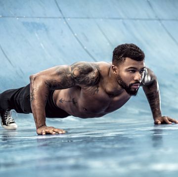 tattooed physical athlete doing pushups on sports field