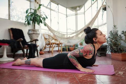 tattooed woman doing yoga at home