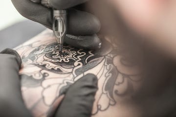 tattooist drawing on arm of client