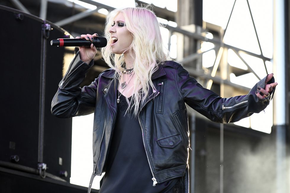 taylor momsen, a young woman sings on stage, she has blonde hair and heavy dark eye makeup, she wears a black dress with leather style jacket