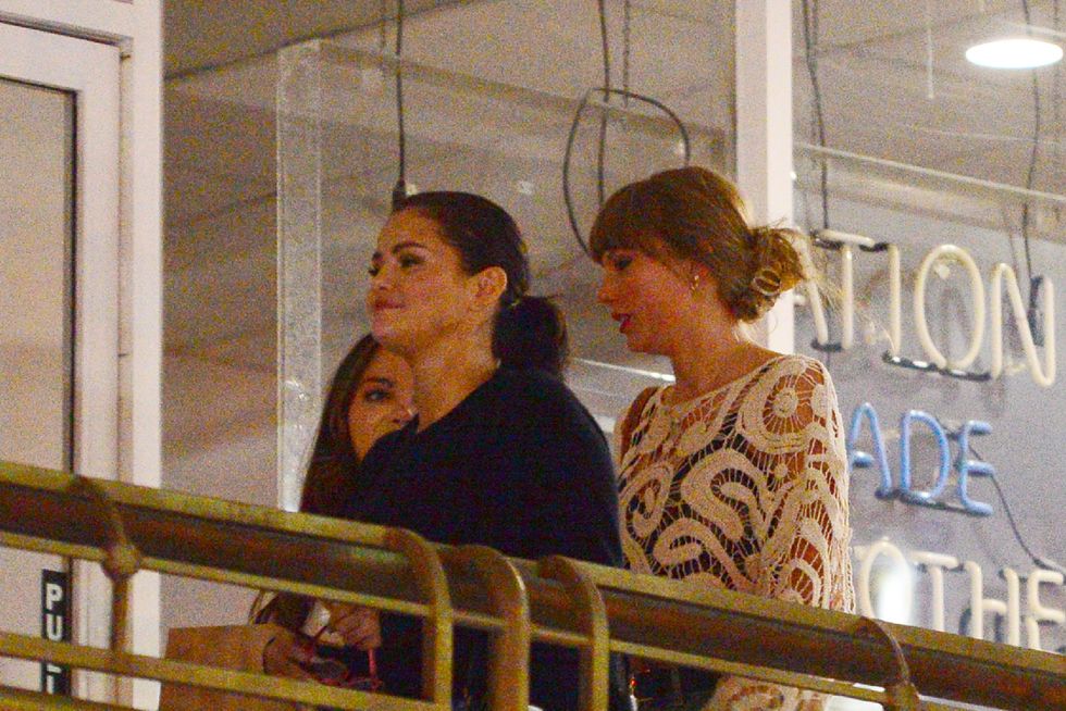 three women walk in a group together behind a golden ornate railing