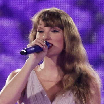 taylor swift wearing a purple ruffle dress on stage during her eras tour, singapore