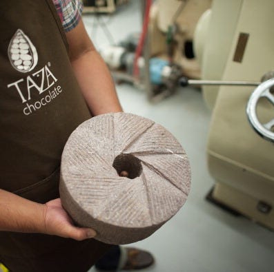 a worker explains the chocolate-making process at the Taza Chocolate Factory, a good housekeeping pick for best factory tours a worker explains the chocolate making process at the taza chocolate factory a good housekeeping pick for best factory tours