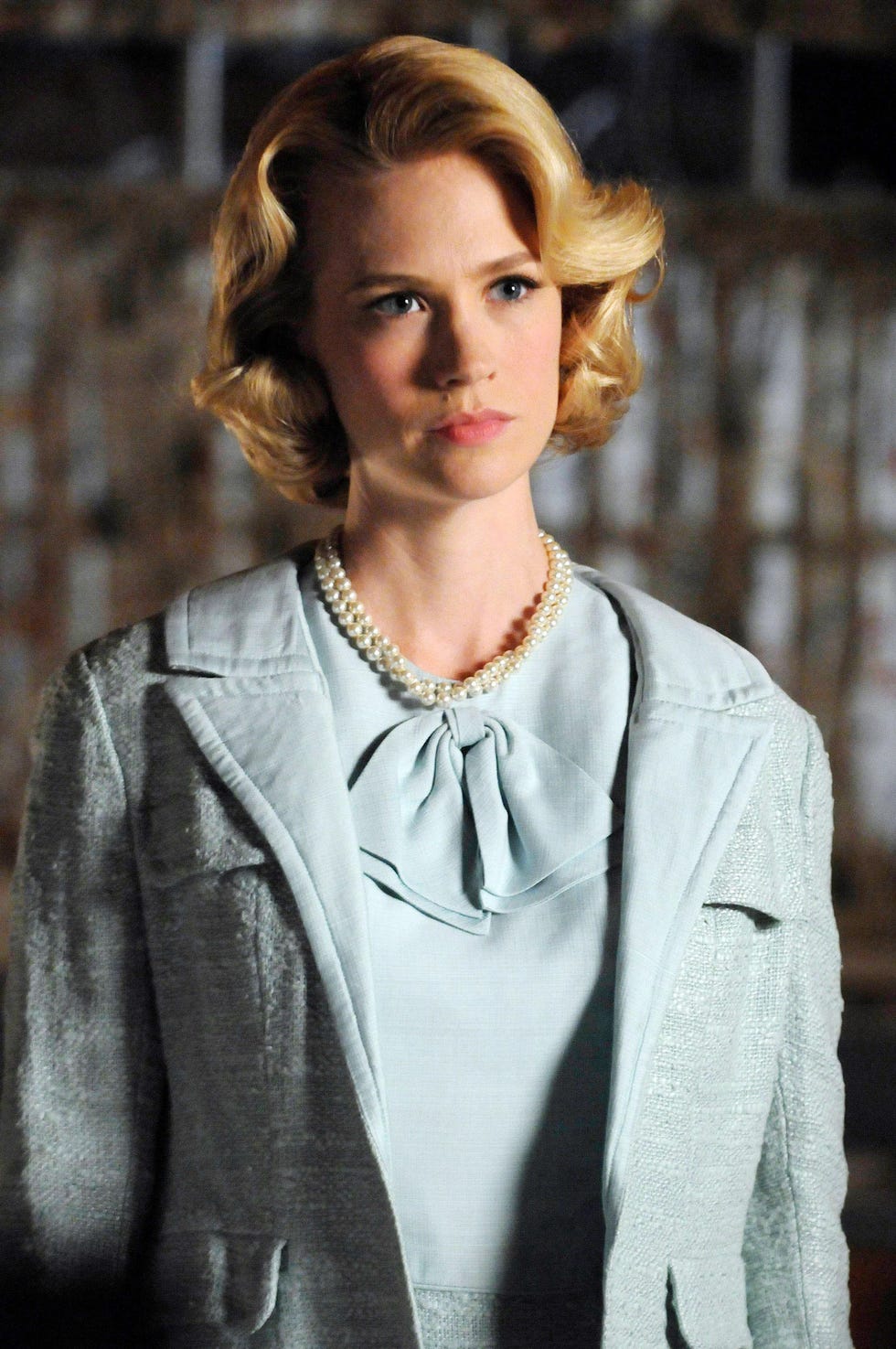 a blonde woman in a blue dress and coat