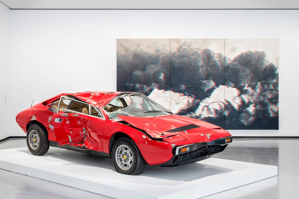 a red car in front of a large picture