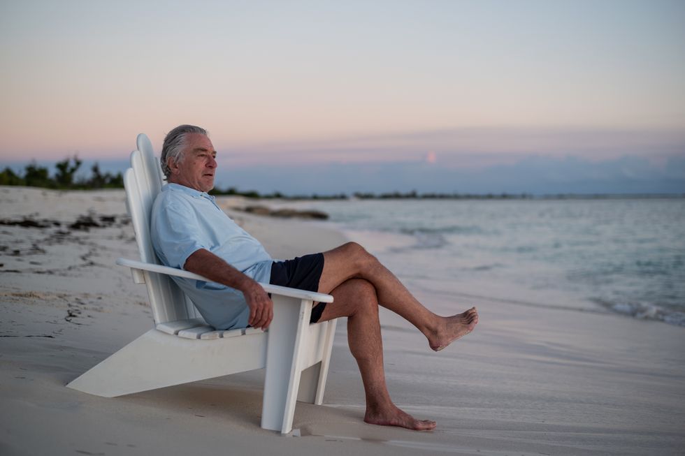 robert de niro sitting in a chair on the beach
