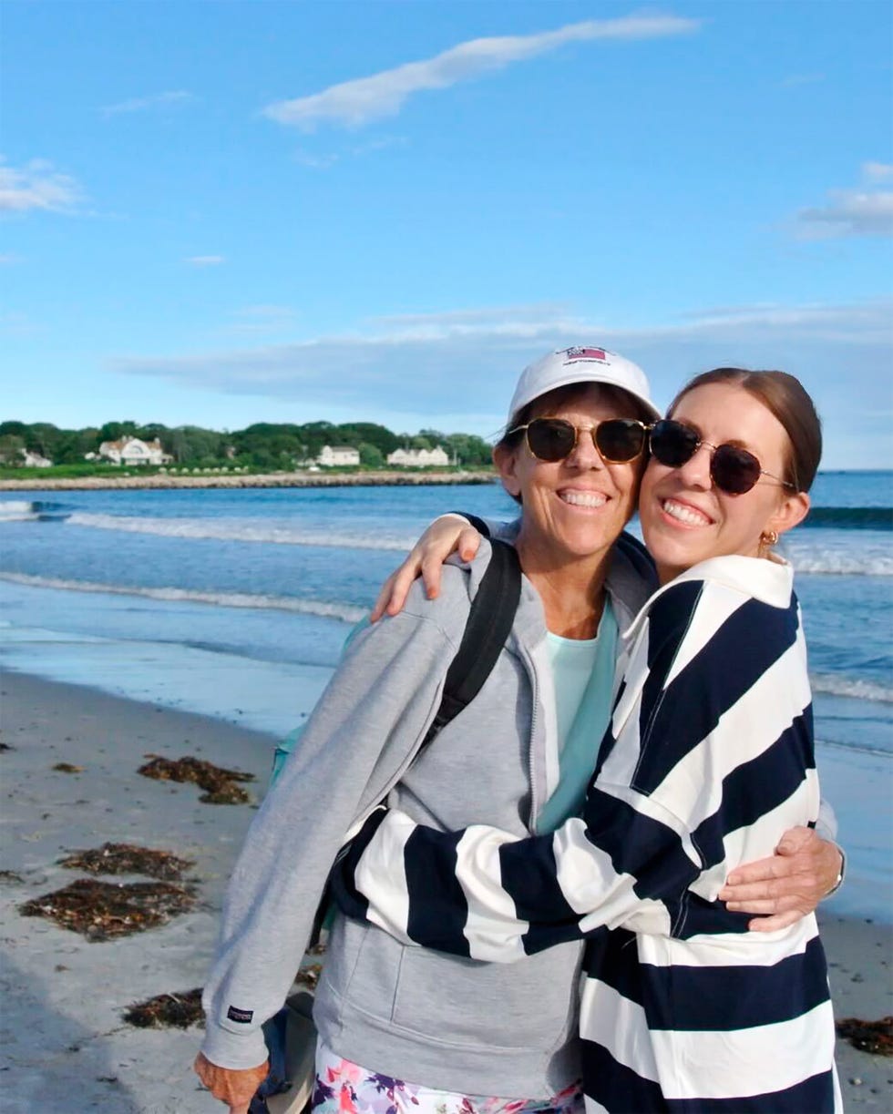 two individuals hugging on the beach with a seaside background