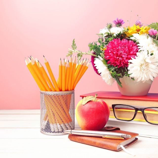 teachers day,flowers pencils stack of books and apple on table empty space background