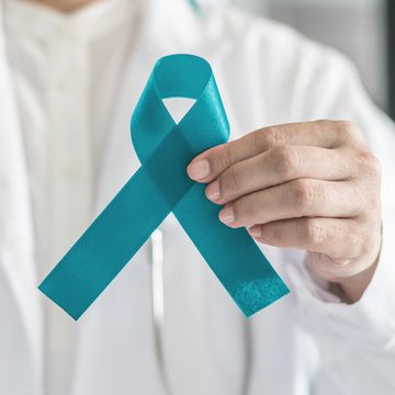 Teal awareness ribbon in doctor's hand, symbolic bow color for supporting patient with Ovarian Cancer, PCOS and PTSD Illness