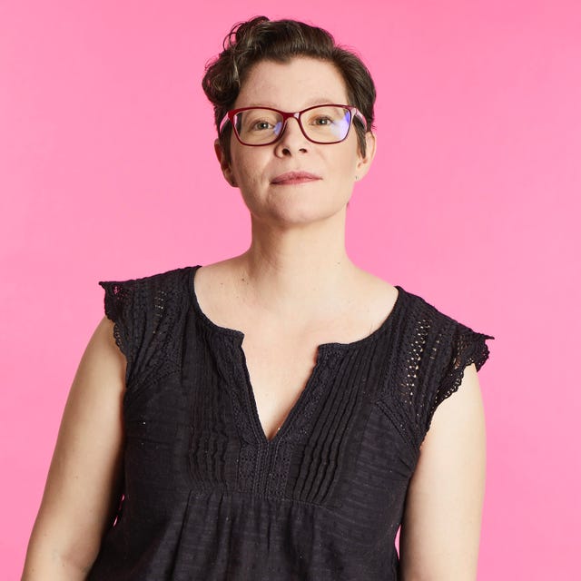 A person wearing a black top against a pink background